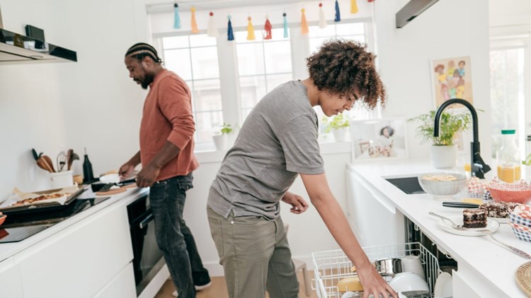 A guy and a girl setting up in the kitchen